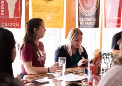 Two women sitting at a table conversing in a group