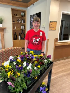 Woman smiling, standing next to flowers