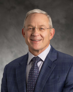 Man in dark blue suit smiling for a headshot