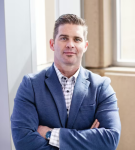 Man in blue suit poses for a headshot 