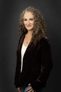 Woman with curly hair and a blazer poses for a professional photo