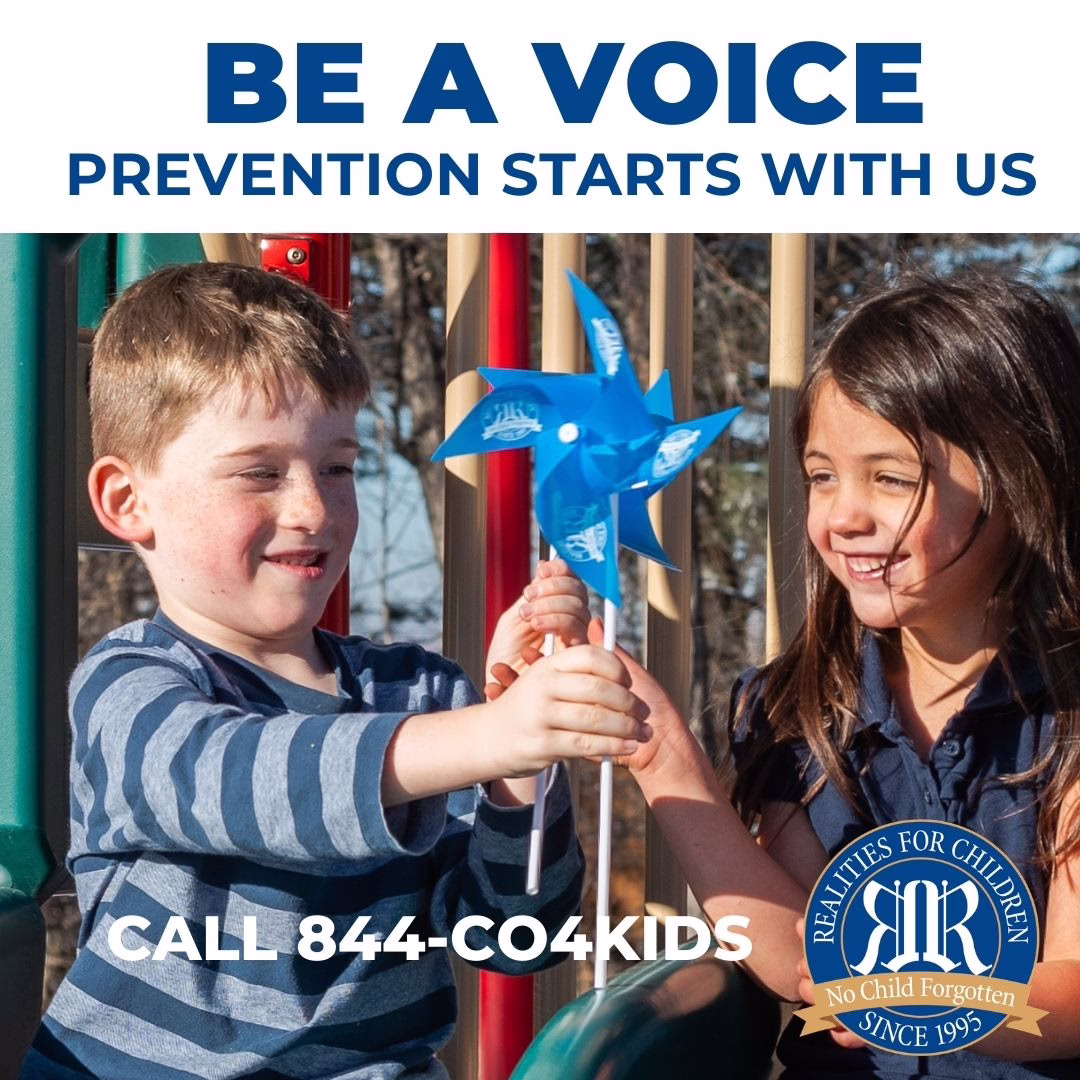 Two smiling children, a boy and a girl, hold a blue pinwheel together at a playground. Text reads: "BE A VOICE. PREVENTION STARTS WITH US. CALL 844-CO4KIDS." Realities For Children logo at bottom right.